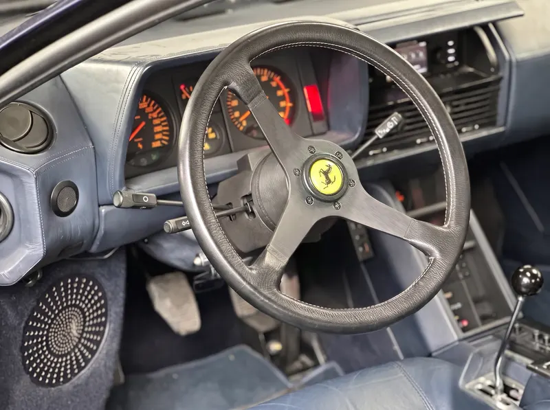 Cockpit eines klassischen Ferrari mit Lederlenkrad, Rundinstrumenten und offener Schaltkulisse